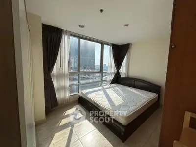 Bright bedroom with large windows and city view, featuring a comfortable bed and elegant curtains.