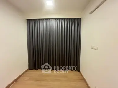 Minimalist room with wooden flooring and dark curtains