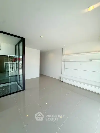 Spacious modern living room with sleek white shelves and glossy tiled flooring.