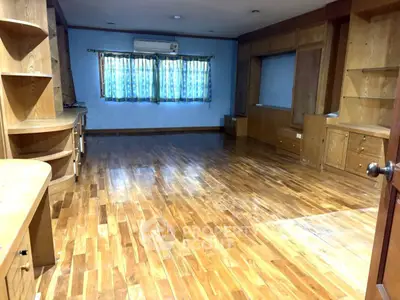 Spacious room with wooden flooring and built-in shelves, perfect for a home office or study area.