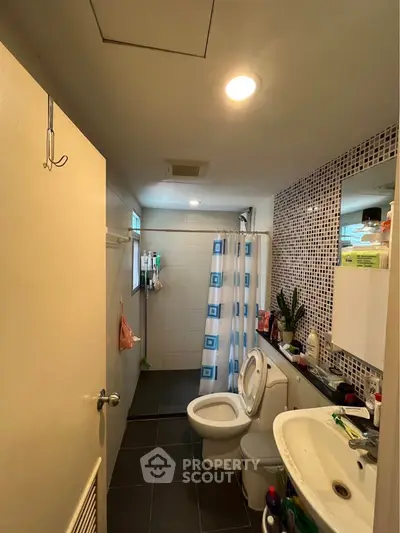 Modern bathroom with shower curtain, tiled walls, and sleek fixtures in a contemporary home.