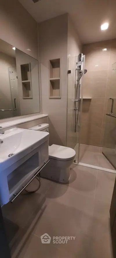 Modern bathroom with glass shower and sleek fixtures in contemporary apartment.