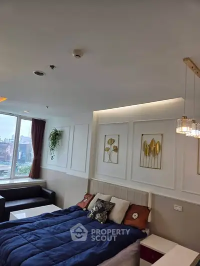 Modern bedroom with stylish decor and city view, featuring elegant wall art and cozy bedding.