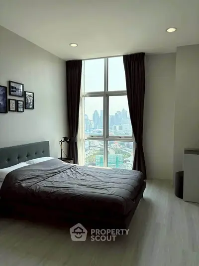 Modern bedroom with city view, featuring large window and stylish decor.