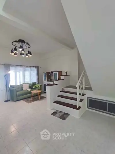 Spacious living room with modern staircase and cozy seating area, perfect for family gatherings.
