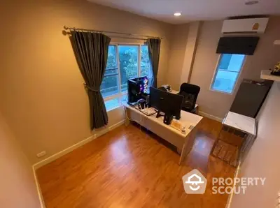 Spacious and well-lit study room with polished hardwood floors, large window with garden view, and modern furnishings, ideal for remote work or creative endeavors.