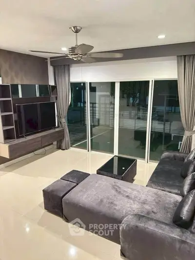 Modern living room with sleek furniture and large glass doors opening to a serene view.