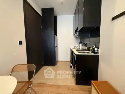 Modern compact kitchen with sleek black cabinets and integrated appliances in a stylish apartment.