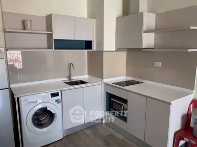 Modern kitchen with washing machine and microwave in sleek white cabinetry