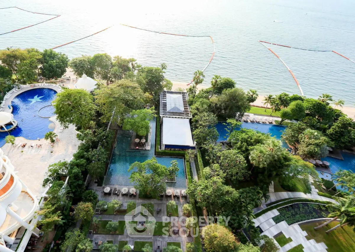 Stunning aerial view of luxury beachfront property with lush gardens and multiple pools.