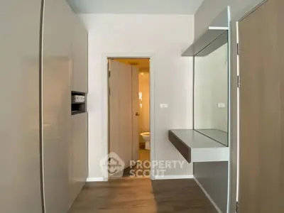 Modern compact bathroom entrance with sleek cabinetry and wooden flooring.