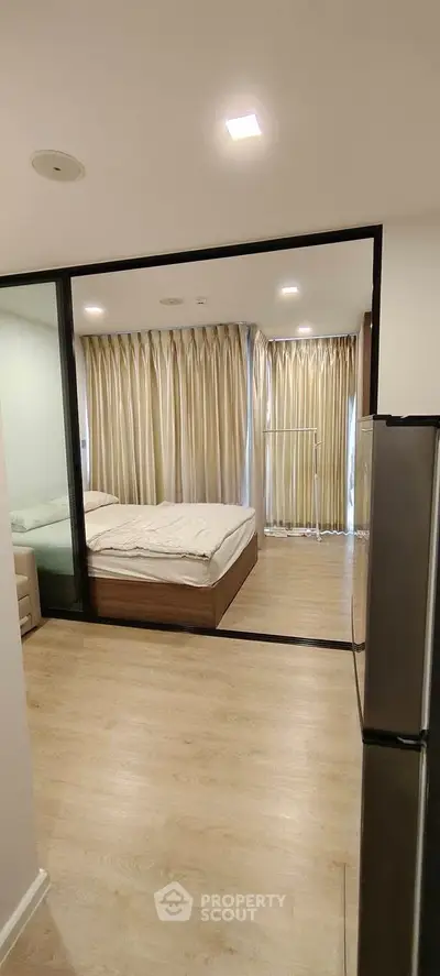 Modern bedroom with glass partition and wooden flooring in a stylish apartment.