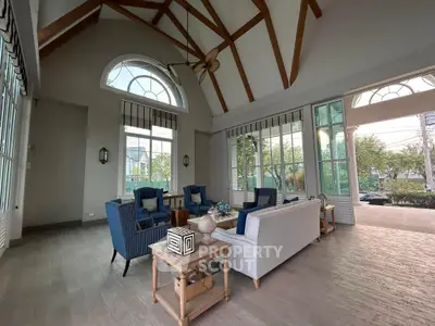 Elegant living room with high ceilings and large windows, featuring stylish blue and white furniture.