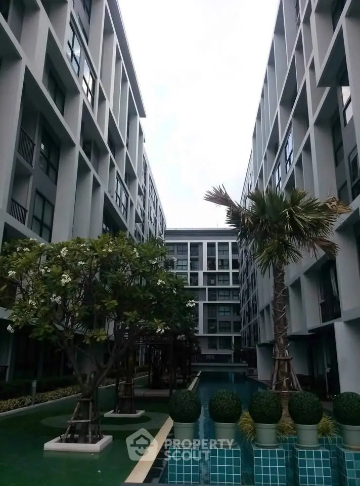 Modern apartment complex with pool and landscaped garden, offering urban living with serene outdoor spaces.