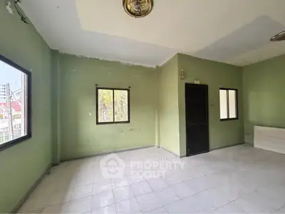Spacious empty room with green walls and large windows, ideal for customization.