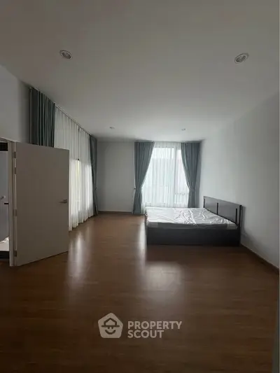 Spacious bedroom with large windows and wooden flooring, perfect for natural light lovers.