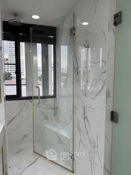 Luxurious bathroom with marble walls and glass shower in modern apartment