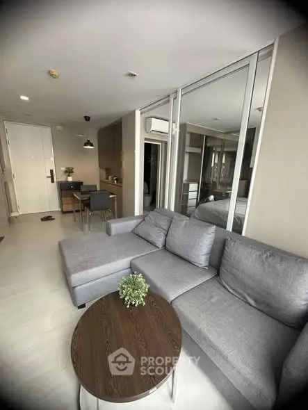 Modern living room with gray sofa and open kitchen layout in a stylish apartment.