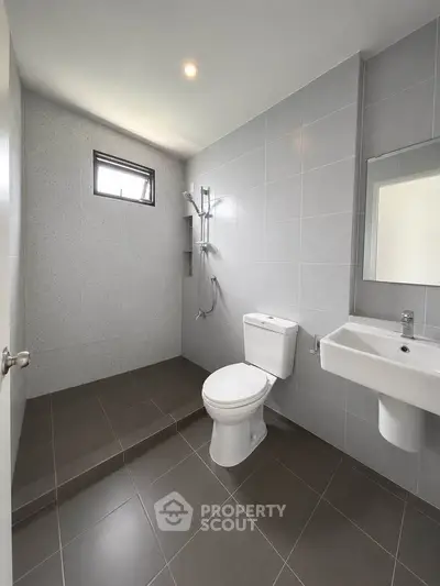 Modern minimalist bathroom with sleek gray tiles and walk-in shower.