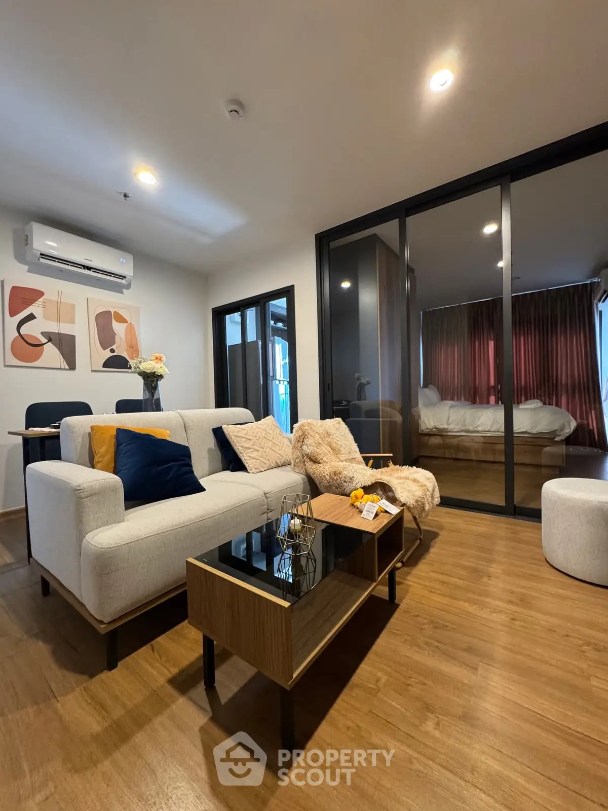 Modern living room with cozy decor and glass partition to bedroom