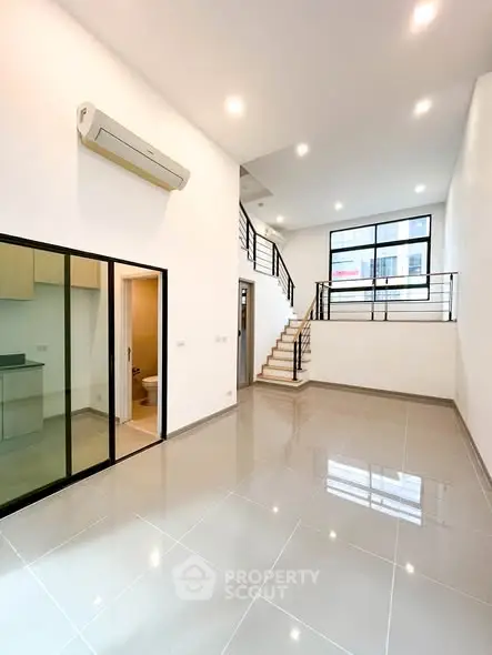 Spacious modern living room with high ceilings and sleek staircase