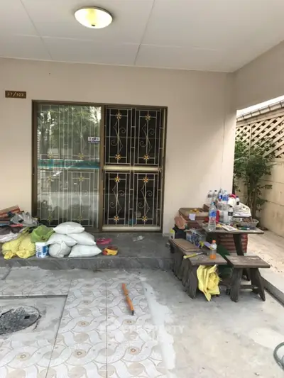 Charming exterior entrance with decorative metal gate and tiled patio, ideal for renovation.