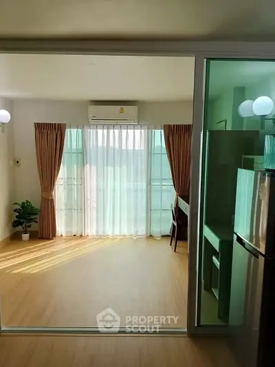 Bright living room with large windows and wooden flooring, featuring modern decor and natural light.