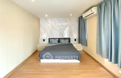 Spacious bedroom with modern decor and natural light, featuring a comfortable bed and elegant curtains.