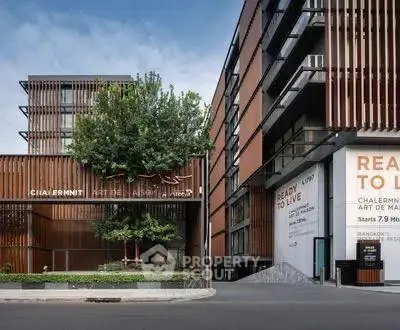 Modern apartment building with sleek design and lush greenery, offering urban living in a prime location.