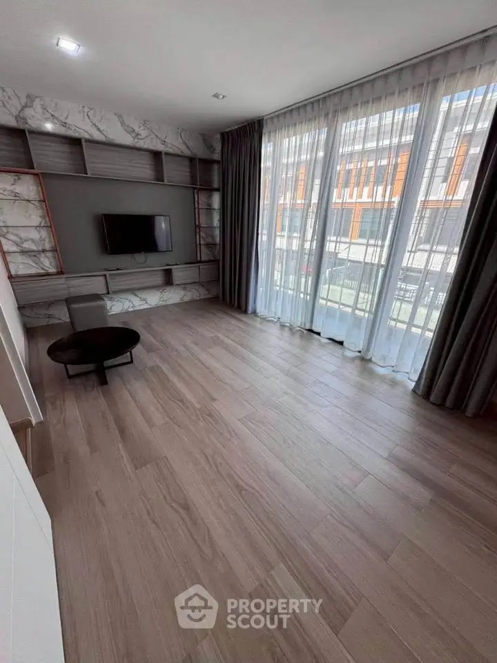 Spacious living room with large windows and modern decor, perfect for natural light lovers.
