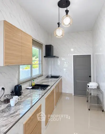 Modern kitchen with marble countertops, sleek cabinetry, and stylish pendant lighting.