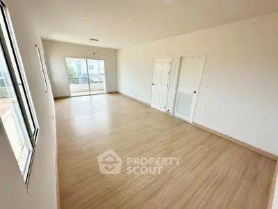 Spacious empty room with wooden flooring and large windows, ideal for customization.
