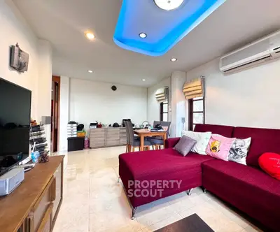 Spacious living room with modern decor and vibrant red sofa, perfect for relaxation and entertainment.