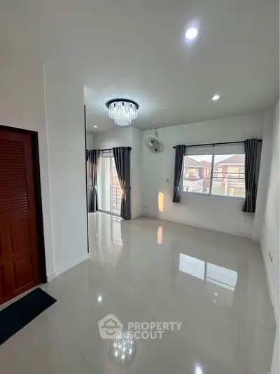 Spacious living room with modern chandelier and large windows in a bright home.