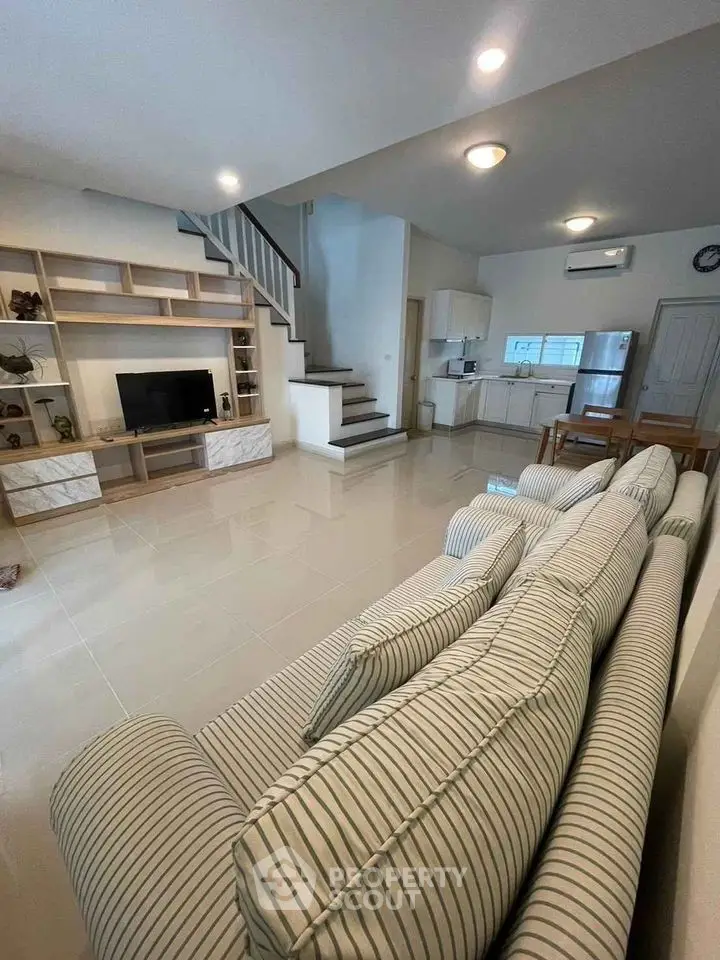 Spacious open-plan living room with modern kitchen and stylish staircase.