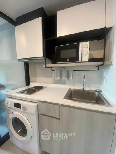 Modern compact kitchen with washing machine and microwave in sleek design