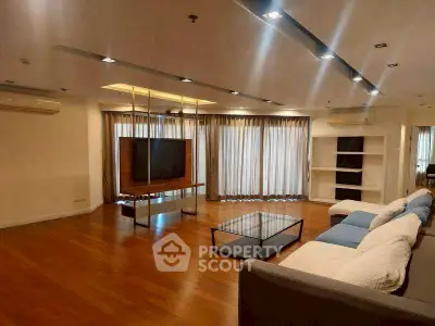 Spacious modern living room with wooden flooring and large windows for natural light.