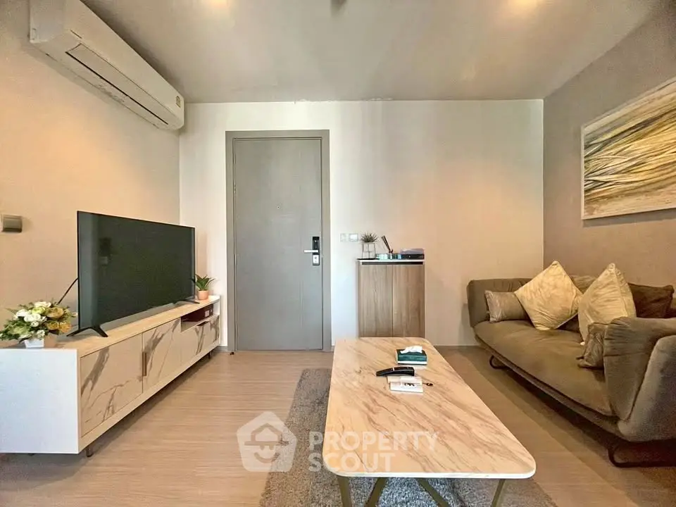 Modern living room with stylish decor and air conditioning, featuring a sleek TV setup and cozy seating area.