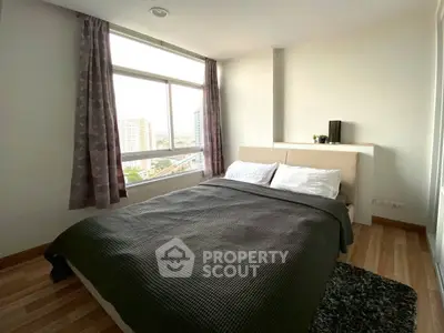 Cozy bedroom with large window offering city views, featuring a comfortable bed and modern decor.