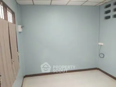 Spacious empty room with light blue walls and tiled ceiling, perfect for customization.