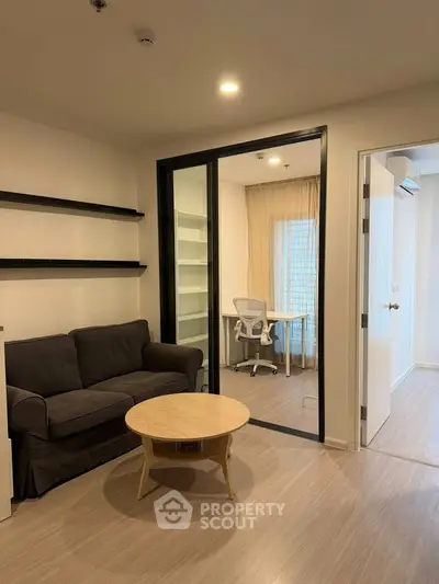Modern living room with study area, featuring sleek furniture and ample natural light.