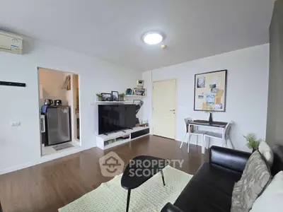 Modern living room with sleek black sofa, wall-mounted TV, and stylish decor in a cozy apartment.