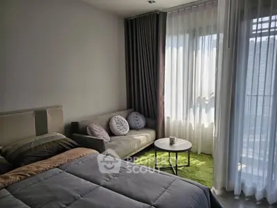 Modern bedroom with cozy sofa and large window offering natural light.