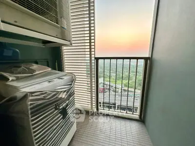 Compact balcony with washing machine and stunning sunset view over cityscape.
