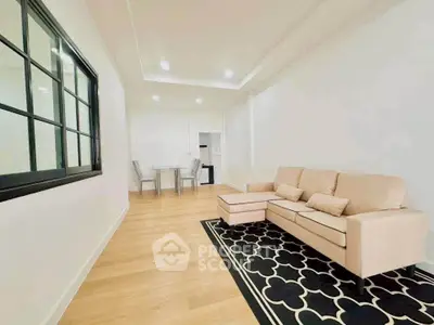 Modern living room with beige sofa and stylish black rug in a bright apartment.