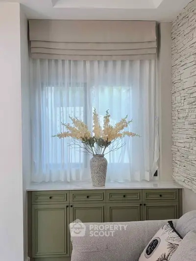 Elegant living room corner with stylish curtains and decorative vase on cabinet.