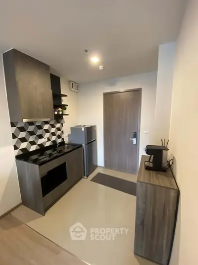 Modern compact kitchen with sleek cabinetry and stylish backsplash in a cozy apartment.