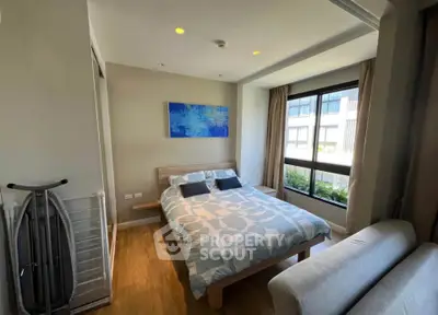 Modern bedroom with large window and stylish decor in a contemporary apartment.