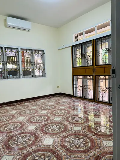 Spacious room with decorative tiled flooring and large windows in a serene residential setting.