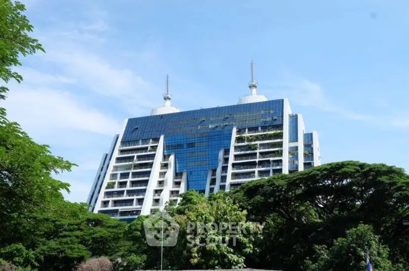 Modern architectural building with lush greenery and blue sky backdrop.